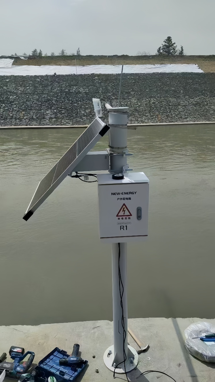 Solar-powered monitoring system installed along a riverbank with waterproof control box
