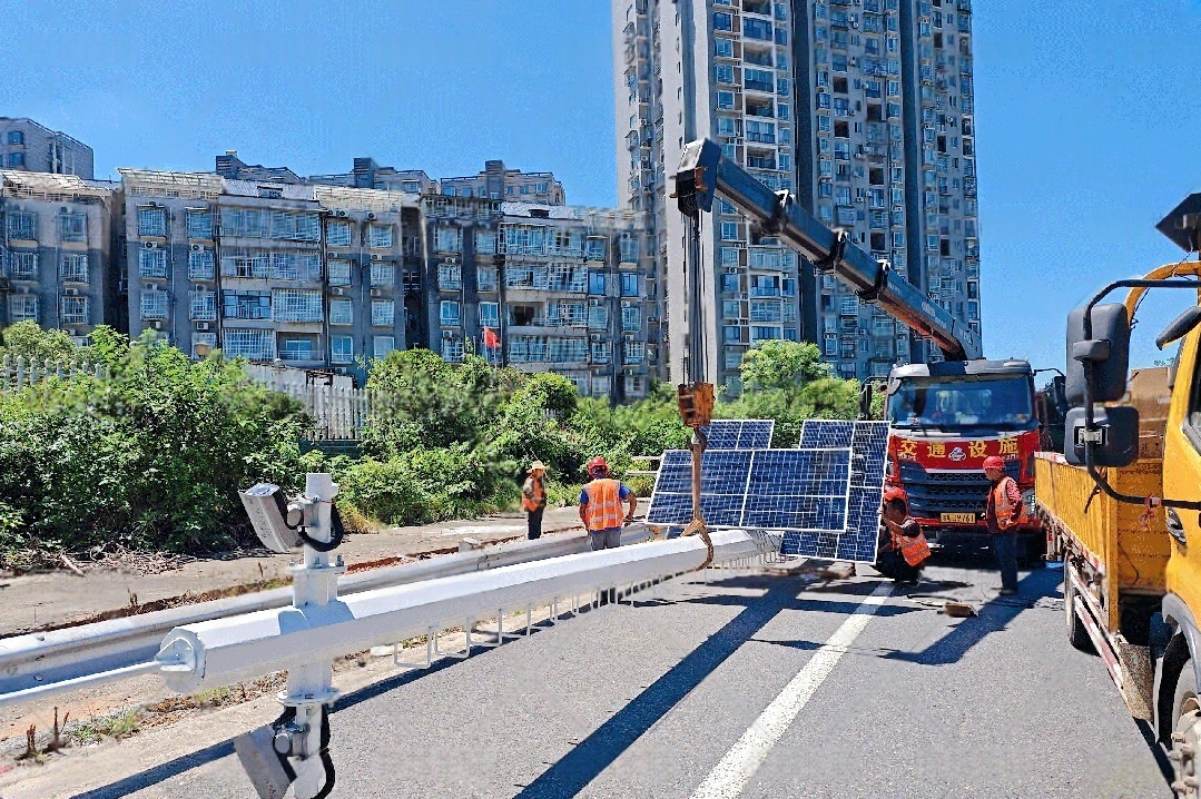 Workers using a crane to install solar-powered CCTV systems on a highway, providing off-grid surveillance and road safety monitoring in China