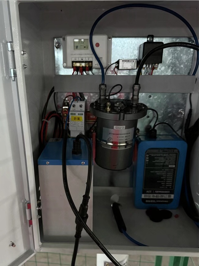 Internal view of a groundwater monitoring system powered by a solar kit, showing the charge controller, LiFePO₄ battery pack, wiring, and sensor interfaces that enable continuous data acquisition and reliable off-grid hydrology operation
