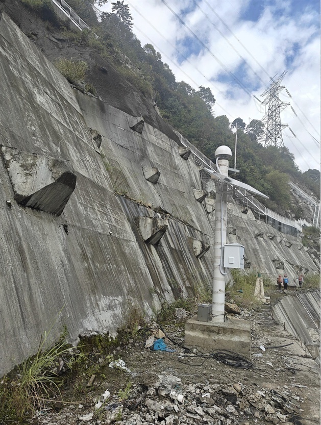 GNSS slope monitoring station deployed on a high-gradient hydropower slope in Weixi, Yunnan, showing exposed rock surfaces, rockfall risk zones, and the surrounding environment that constrains power system design and maintenance access