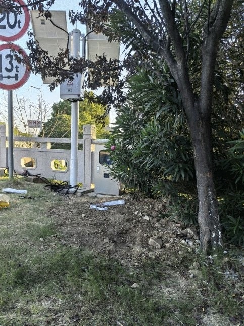 Pole-mounted telemetry cabinet beside roadside vegetation in Jiangsu, China confirms that a solar-powered hydrological monitoring system can preserve warning-data transmission reliability and enclosure stability under humid outdoor exposure, partial vegetation shielding, dispersed monitoring deployment, and constrained maintenance-access conditions